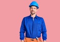 Young handsome man wearing worker uniform and hardhat smiling looking to the side and staring away thinking Royalty Free Stock Photo
