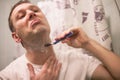 Young handsome man in white t-shirt shaves in front of bathroom mirror in the morning. Royalty Free Stock Photo