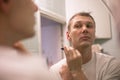 Young handsome man in white t-shirt shaves in front of bathroom mirror in the morning. Royalty Free Stock Photo