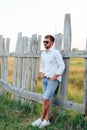 Young handsome man in a white shirt and jeans shorts outdoors Royalty Free Stock Photo