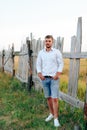 Young handsome man in a white shirt and jeans shorts outdoors Royalty Free Stock Photo