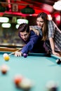 Young handsome man and woman flirting while playing snooker