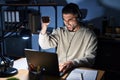 Young handsome man working using computer laptop at night angry and mad raising fist frustrated and furious while shouting with Royalty Free Stock Photo
