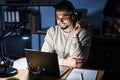 Young handsome man working using computer laptop at night with a big smile on face, pointing with hand and finger to the side Royalty Free Stock Photo