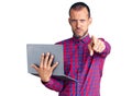 Young handsome man working using computer laptop pointing with finger to the camera and to you, confident gesture looking serious Royalty Free Stock Photo