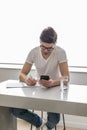 Young handsome man is writing something on paper notebook and holding mobile smart phone at home. business concept Royalty Free Stock Photo