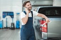 Young handsome mechanic wearing uniform leaning on pickup trunk talking on the phone in car service center Royalty Free Stock Photo