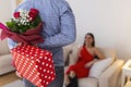 Young handsome man holding a gift and flowers behind his back to surprise his girlfriend, romantic happy couples sharing gift Royalty Free Stock Photo