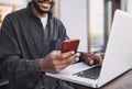 Young handsome men texting on his smartphone and using laptop computer in a city. Royalty Free Stock Photo