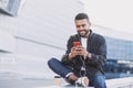 Young handsome men using smartphone in a city. Smiling student man texting on his mobile phone. Royalty Free Stock Photo