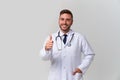 Young handsome modern doctor in a white medical gown stands in the studio on a white background. Student trainee of a medical Royalty Free Stock Photo