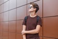 Young handsome modern hipster man in black stylish sunglasses in a stylish t-shirt in a black sports backpack near a wall Royalty Free Stock Photo