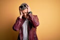 Young handsome modern man wearing fashion leather jacket and sunglasses over yellow background suffering from headache desperate Royalty Free Stock Photo