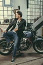 young handsome motorcyclist in black leather jacket with classic motorbike