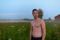 Young handsome muscular man thinking shirtless against grass field with fog in the break of dawn