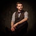 Young handsome old-fashioned man with beard posing on dark background. Royalty Free Stock Photo