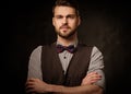 Young handsome old-fashioned man with beard posing on dark background.