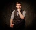 Young handsome old-fashioned man with beard posing on dark background. Royalty Free Stock Photo