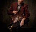 Young handsome old-fashioned man with briefcase posing on dark background. Royalty Free Stock Photo