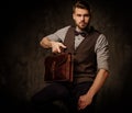 Young handsome old-fashioned man with briefcase posing on dark background. Royalty Free Stock Photo