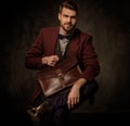 Young handsome old-fashioned man with briefcase posing on dark background. Royalty Free Stock Photo