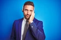 Young handsome operator man wearing call center headset over blue  background thinking looking tired and bored with Royalty Free Stock Photo