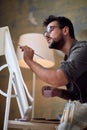 Young handsome painter working on details of the painting