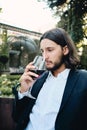 Young handsome pensive brunette bearded man thoughtfully drinking wine in restaurant outdoor Royalty Free Stock Photo