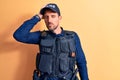 Young handsome policeman wearing police uniform and bulletprof over yellow background surprised with hand on head for mistake, Royalty Free Stock Photo