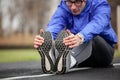 Shot of a young handsome professional runner stretching his feet Royalty Free Stock Photo