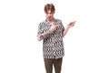 young handsome red-haired man dressed in a summer shirt with a rhombus print points his hand to the side