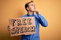 Young handsome redhead man asking for freedom holding banner with free speech message serious face thinking about question with Royalty Free Stock Photo