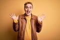 Young handsome redhead man wearing casual leather jacket over isolated yellow background celebrating crazy and amazed for success Royalty Free Stock Photo