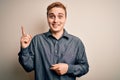 Young handsome redhead man wearing casual shirt standing over isolated white background with a big smile on face, pointing with Royalty Free Stock Photo