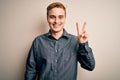 Young handsome redhead man wearing casual shirt standing over isolated white background smiling with happy face winking at the Royalty Free Stock Photo