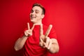 Young handsome redhead man wearing casual t-shirt over isolated red background smiling looking to the camera showing fingers doing Royalty Free Stock Photo