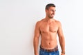 Young handsome shirtless man showing muscular body over isolated background looking away to side with smile on face, natural Royalty Free Stock Photo