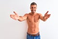 Young handsome shirtless man showing muscular body over isolated background looking at the camera smiling with open arms for hug Royalty Free Stock Photo