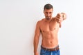 Young handsome shirtless man showing muscular body over isolated background looking unhappy and angry showing rejection and