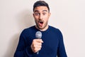 Young Handsome Singer Man With Beard Singing Song Using Microphone Over White Background Scared And Amazed With Open Mouth For