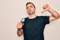 Young handsome singer man with blue eyes singing using microphone over white background with angry face, negative sign showing Royalty Free Stock Photo