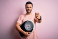 Young handsome slim sportsman with beard holding scale over isolated pink background annoyed and frustrated shouting with anger,