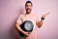 Young handsome slim sportsman with beard holding scale over isolated pink background very happy and excited, winner expression