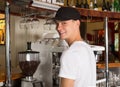 Young handsome smiling barista in white shirt and baseball hat s