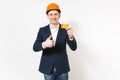 Young handsome smiling businessman in dark suit, protective construction helmet holding credit card and showing thumb up Royalty Free Stock Photo