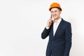 Young handsome smiling businessman in dark suit, protective construction orange helmet talking on mobile phone isolated Royalty Free Stock Photo