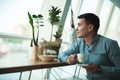 Young handsome smiling businessman drinking his hot coffee and eating salad for lunch during break at trendy cafe near Royalty Free Stock Photo