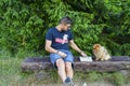 Young handsome smiling man reading outdoor with a dog