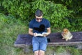 Young handsome smiling man  reading outdoor with a dog Royalty Free Stock Photo