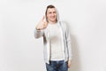 Young handsome smiling man in t-shirt, blue jeans and light sweatshirt shows gesture thumbs up and rejoices on Royalty Free Stock Photo